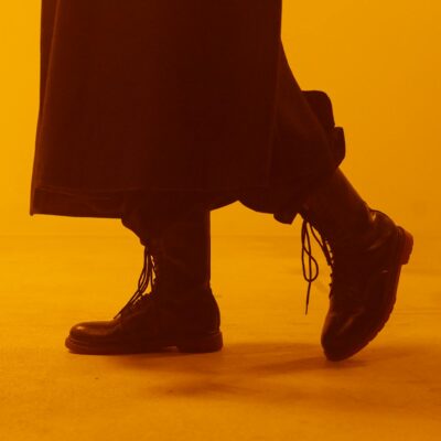 Close-up of black boots with laces in a dramatic, warm-toned studio setting.