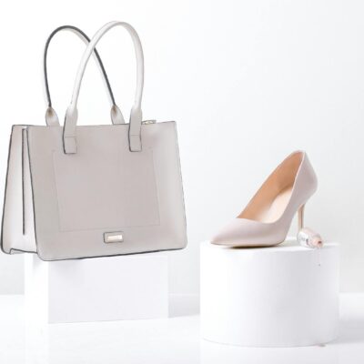Stylish white leather handbag and heel on white background, highlighting elegance and simplicity.