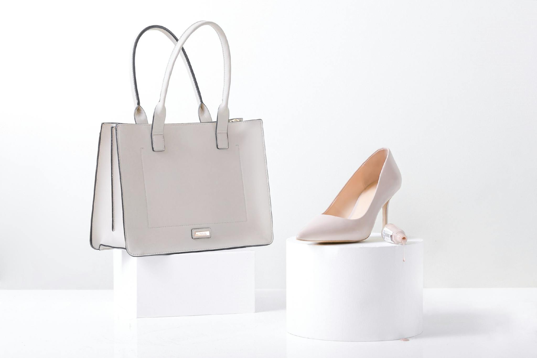Stylish white leather handbag and heel on white background, highlighting elegance and simplicity.